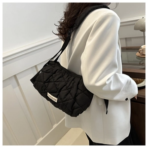 Close-up of a black quilted puffer tote bag on a model in a modern cafe setting