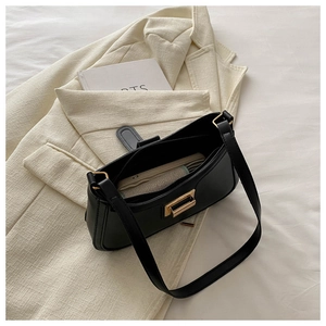 Detail of minimalist black underarm bag with gold buckle on cream blazer background