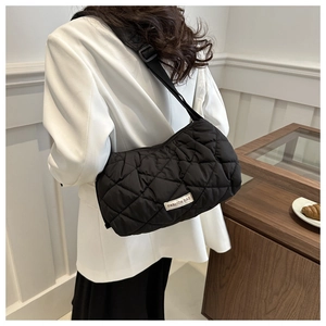 Detail of black quilted puffer shoulder bag with fashion tag and adjustable strap