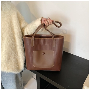 Detail of woven texture tote bag with front pocket and dual handles in chocolate brown