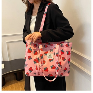 Detailed shot of pink tote bag with red strawberry print and fabric logo patch