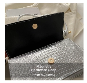 Close-up of the hardware magnetic clasp on silver crocodile pattern shoulder bag