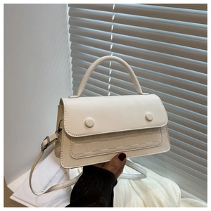 Macro detail of white checkered crossbody bag featuring textured matte finish and flap buckles