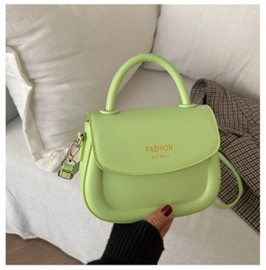 Close-up of neon green mini saddle bag with Fashion H.C gold lettering and metal buckle