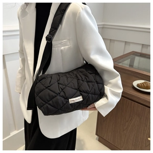 Detail of black quilted puffer bag showing soft rhombus texture and adjustable strap