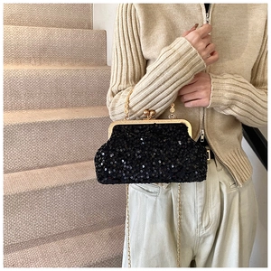 Détail d'un sac à main élégant à paillettes noires avec chaîne dorée tenu par un mannequin