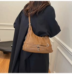 Detail of vintage brown PU leather shoulder bag with adjustable straps and silver rings