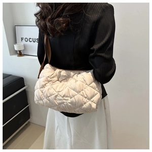Detail of beige quilted shoulder bag with wide coffee brown strap and soft padded texture