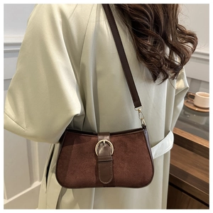 Close-up of retro brown frosted shoulder bag with gold buckle on a model's beige trench coat