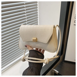 Close-up of creamy white baguette bag with crocodile pattern and gold buckle detail