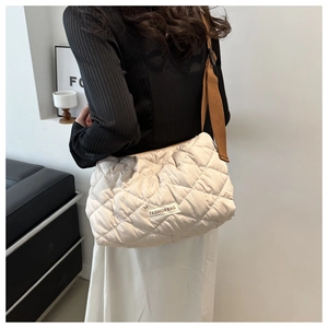 Detail of quilted puffer bag with rectangle fashion label and wide brown strap