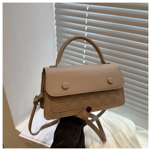 Detail view of beige crossbody bag with textured checkered pattern and metal snap buttons