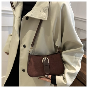 Brown frosted suede shoulder bag with vintage metal buckle shown on a trench coat