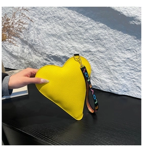 Detail of yellow heart-shaped bag with lychee texture and LOVE embroidered wrist strap