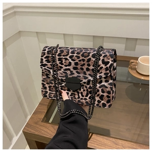 Detail of leopard print crossbody bag with metallic chain strap and black shield buckle