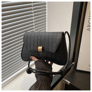 Close-up of black crocodile pattern leather shoulder bag with vintage gold metal buckle clasp