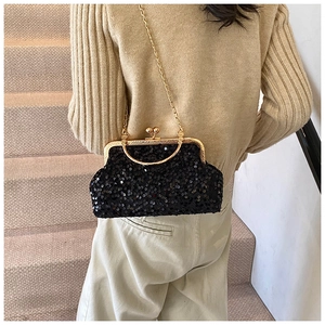 Détail du sac coquillage à paillettes noires avec fermoir doré et bandoulière sur modèle