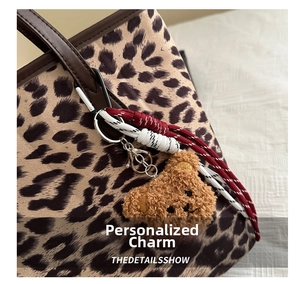 Détail du charm ours en peluche sur sac léopard avec corde tressée et fermoir en métal