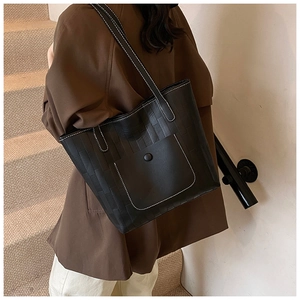 Detail of black textured PU leather tote bag with white contrast stitching and front pocket