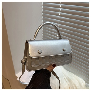 Close-up of silver crossbody bag with textured checkerboard pattern and glossy finish