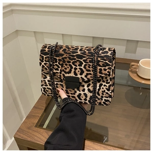 Close-up of leopard print crossbody bag with chunky black metal chain and shield buckle