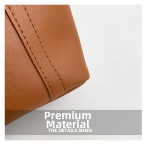 Detailed close-up of brown leather texture and double-stitched seams on the tote bag