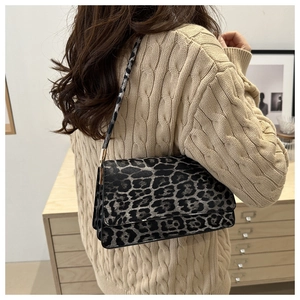 Detail of leopard print shoulder bag with rectangle flap worn over a beige knit sweater
