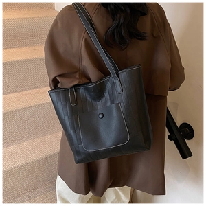 Detail of black PU tote bag with white contrast stitching and a large front snap pocket