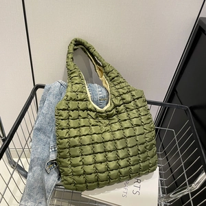 Quilted green bubble tote bag in a metal basket with casual styling and denim jacket