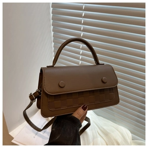 Detailed view of brown leather bag featuring woven lattice texture and round decorative buckle