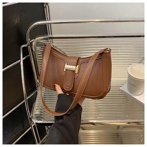 Close-up of brown square baguette bag with gold metal buckle and stitching details