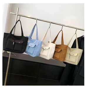 Detailed view of large nylon tote bags in five different colors hanging on a rack
