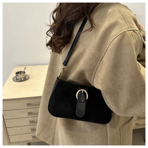 Detail of black matte shoulder bag with gold metal ring buckle and leather strap