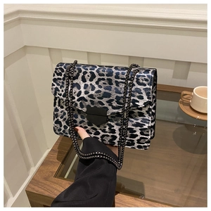 Detail of blue leopard print handbag with metallic clasp and chain strap in hand