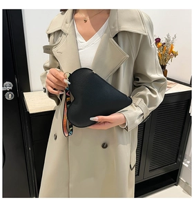 Detail of black heart-shaped leather bag with stylish colorful letter ribbon strap