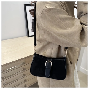 Detail of black matte shoulder bag with silver ring buckle shown on a model