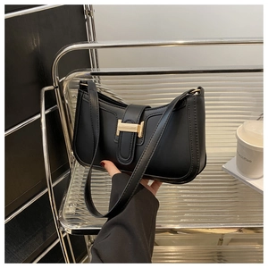 Close-up of minimalist black leather shoulder bag with elegant gold H-shaped metal buckle