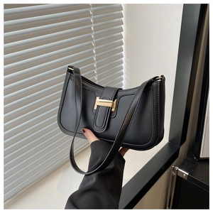 Detail of a black leather shoulder bag with a vintage gold H-shaped metal buckle clasp