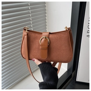 Close-up of brown shoulder bag featuring suede texture and gold buckle detail