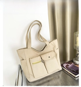 Detail of khaki canvas tote bag featuring functional front zipper and flap pockets
