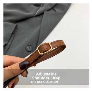 Detail of adjustable brown leather shoulder strap with gold metal buckle and stitching