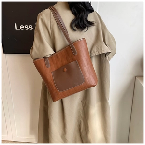 Detail of brown faux leather tote bag with brick texture and dark brown outer pocket