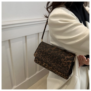 Side view of leopard print shoulder bag worn with a white blazer and black outfit