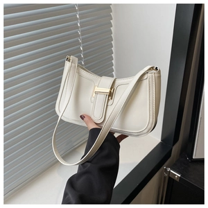 Detailed view of off-white leather underarm bag featuring a glossy gold metal lock