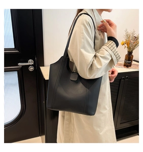 Detail view of a minimalist black matte leather tote bag with vertical decorative stitching