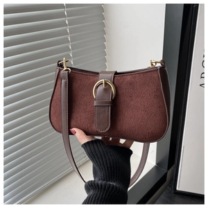 Detail of vintage brown suede baguette bag with gold horseshoe buckle and smooth leather