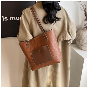 Close-up of brown textured PU leather tote bag with contrast pocket and vertical stitching