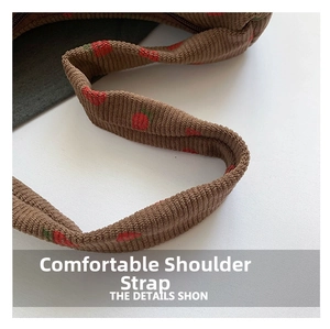 Close-up of deep brown corduroy shoulder strap with red strawberry embroidery detail