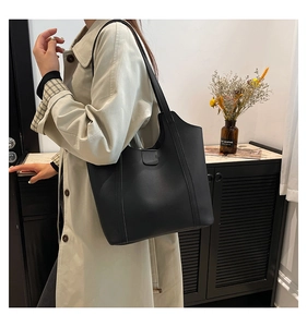 Minimalist black tote bag in PU leather shown on shoulder with clean urban aesthetic