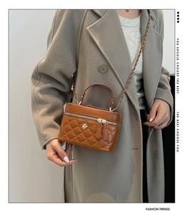 Detail of a brown quilted leather vanity bag with a gold flower buckle and chain strap